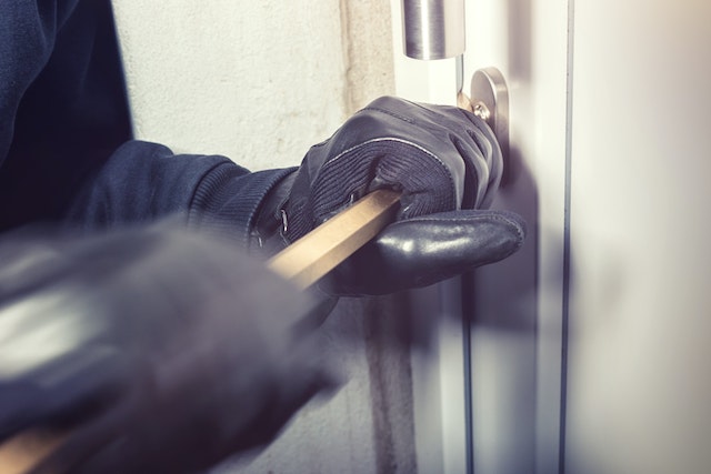 person using crowbar to break open locked door